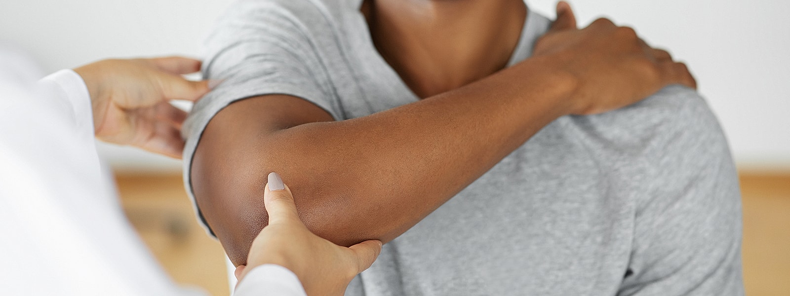 Medical professional examining a patient's elbow.